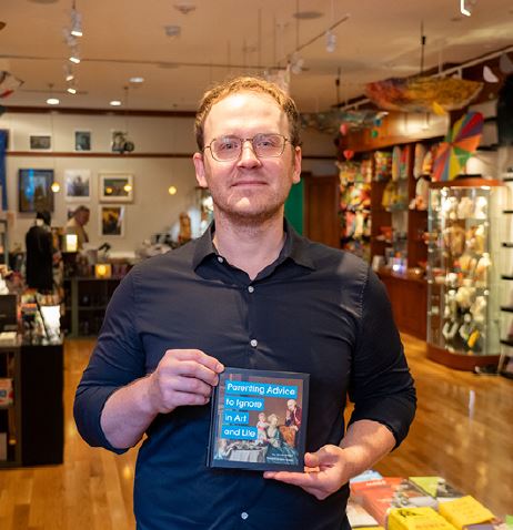 Thomas holding up a book in the shop